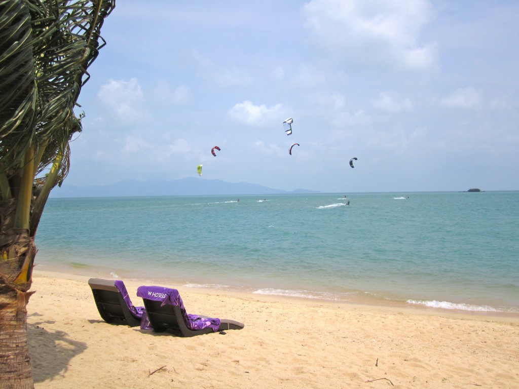 a beach with chairs and kites in the sky