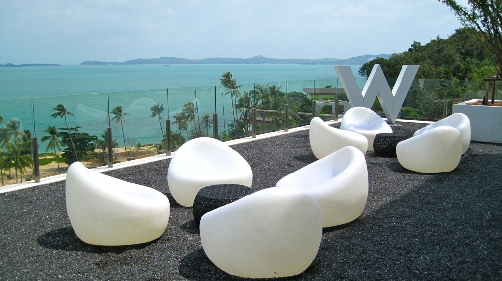 a group of white chairs on a black gravel surface