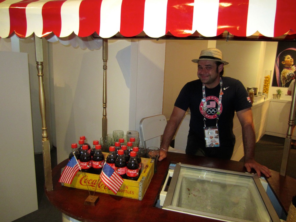 a man standing behind a counter with a soda and a box of bottles