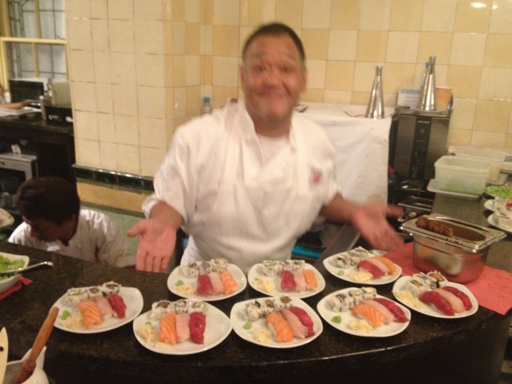 a man in a chef's uniform standing behind plates of food