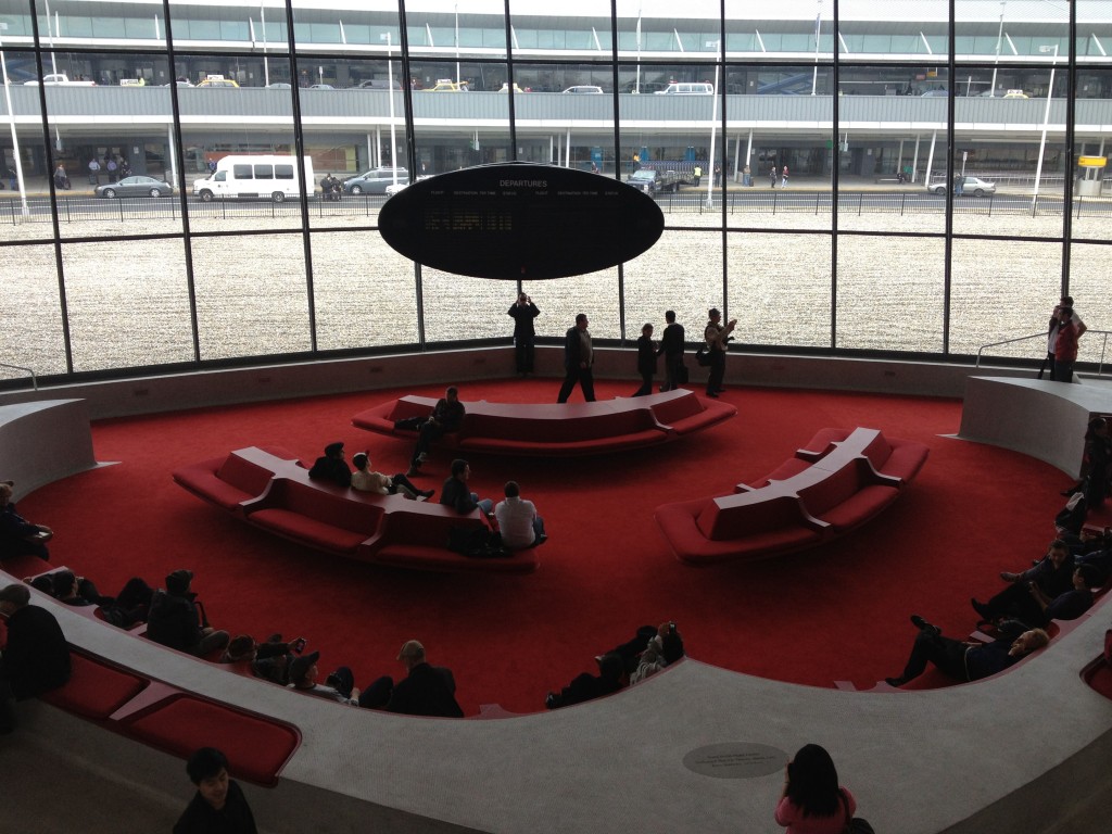 a group of people sitting in a circular area with red couches