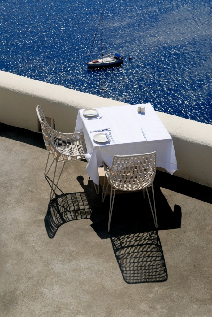 a table and chairs on a balcony overlooking a body of water