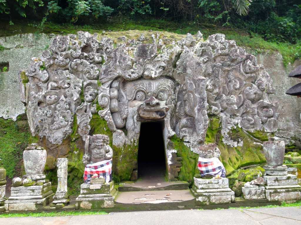 a stone cave with a door and a doorway with Goa Gajah in the background