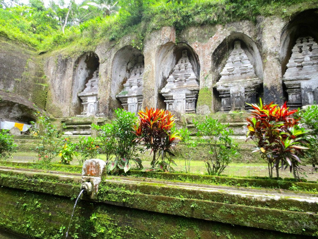 a stone wall with a fountain and a group of statues