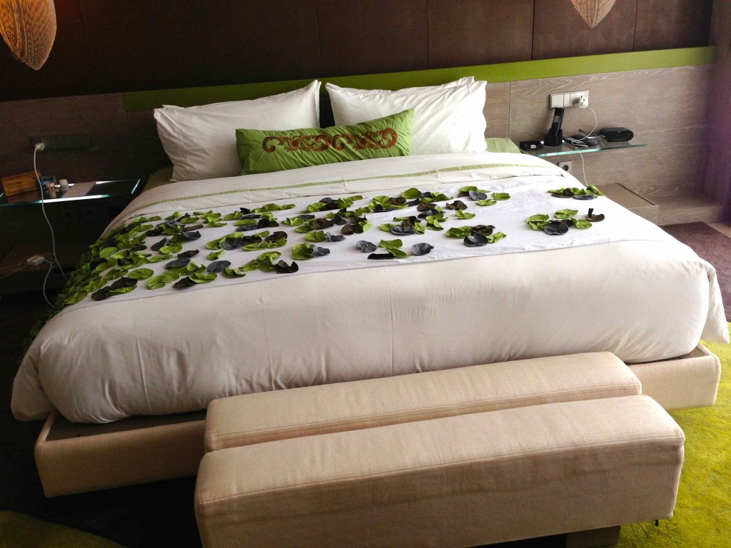 a bed with white sheets and green leaves on it
