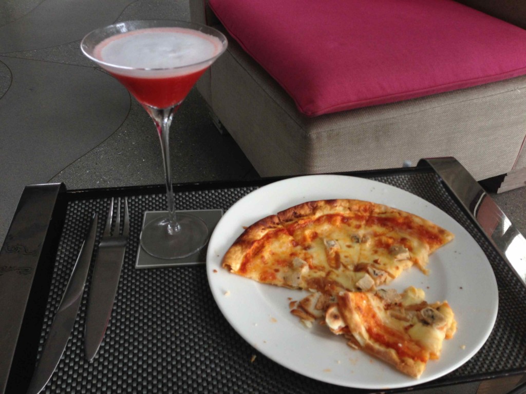 a pizza on a plate next to a martini glass