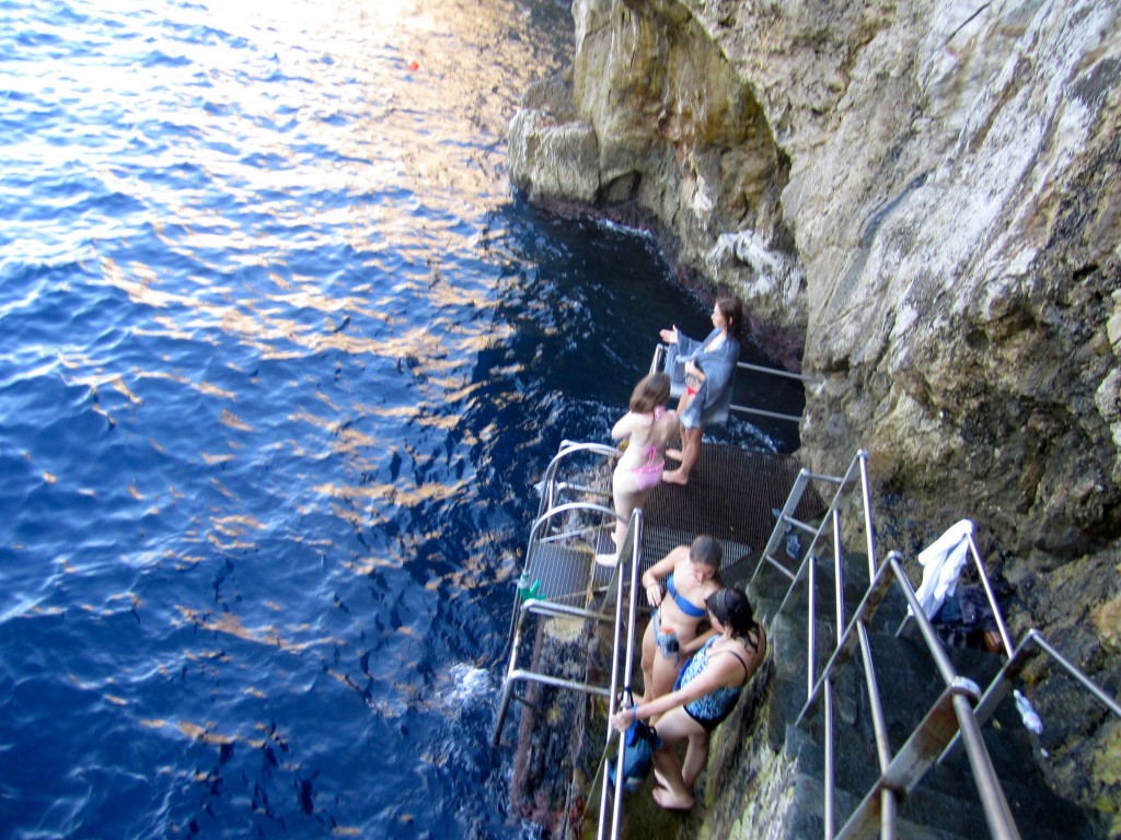 people standing on a metal staircase next to a body of water