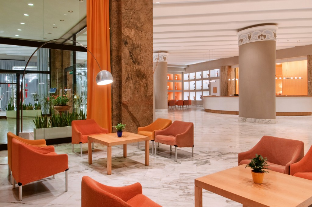 a lobby with orange chairs and tables