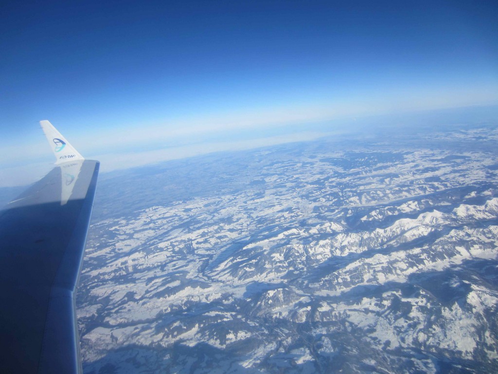 an airplane wing with snow covered mountains