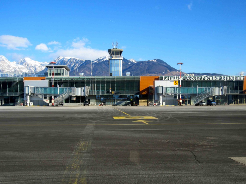 a building with a tower and a parking lot with mountains in the background