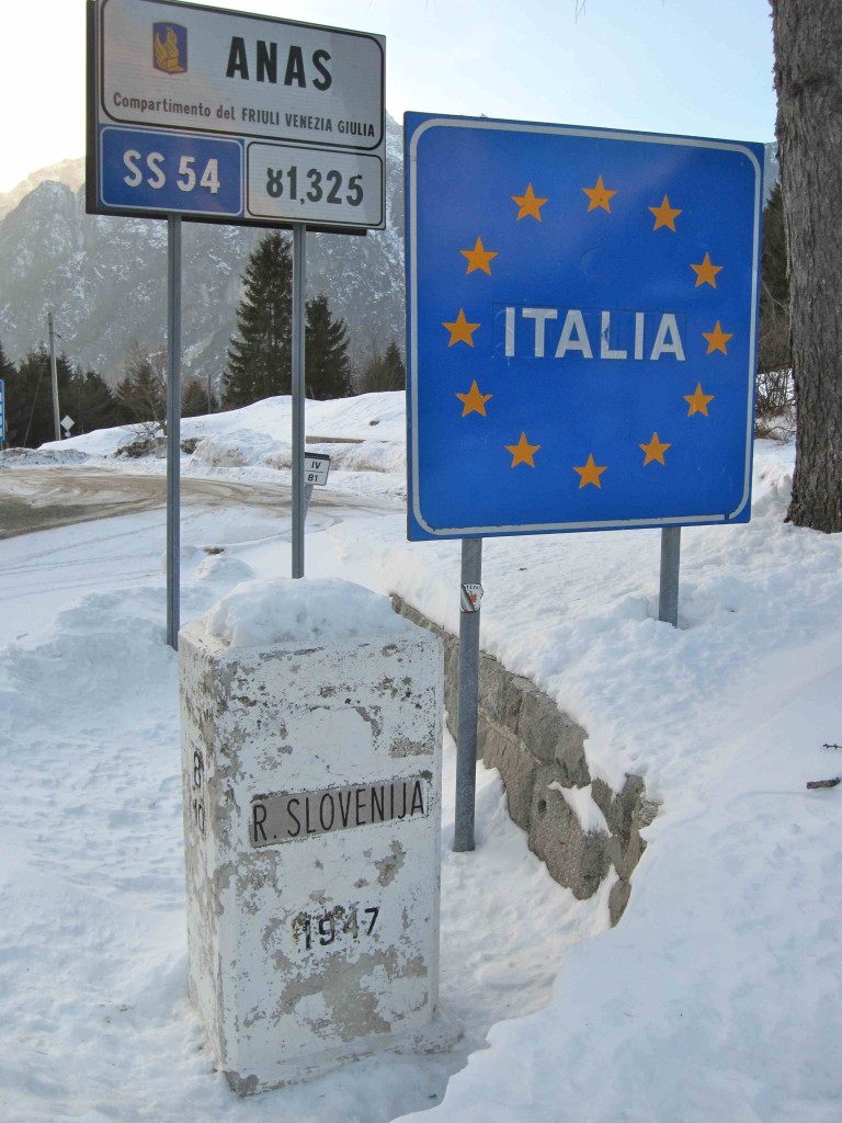 a blue sign with yellow stars on it and a stone post in the snow