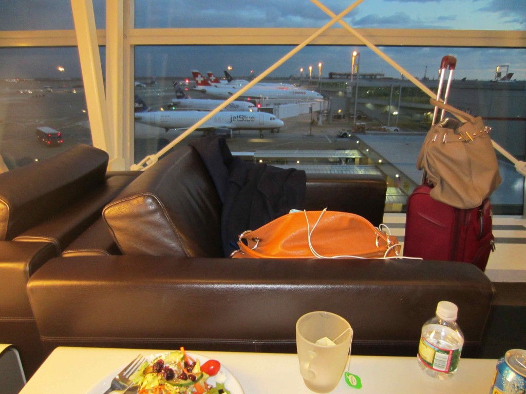 a couch with luggage and a plate of salad and a glass of water