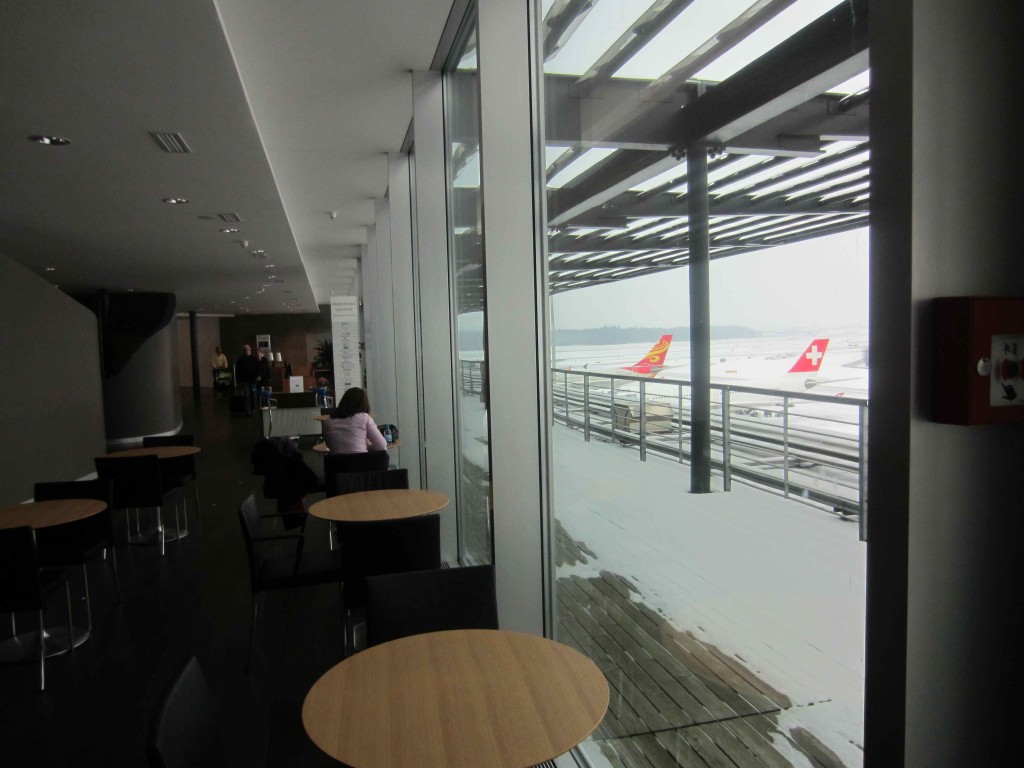 a room with tables and chairs and a window with a plane in the background