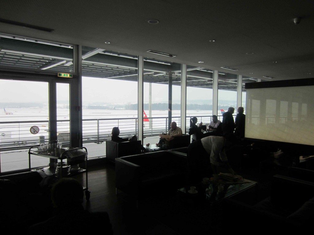 a group of people sitting in a room with large windows