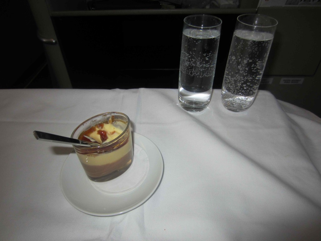 a dessert in a glass cup with a spoon on a white table