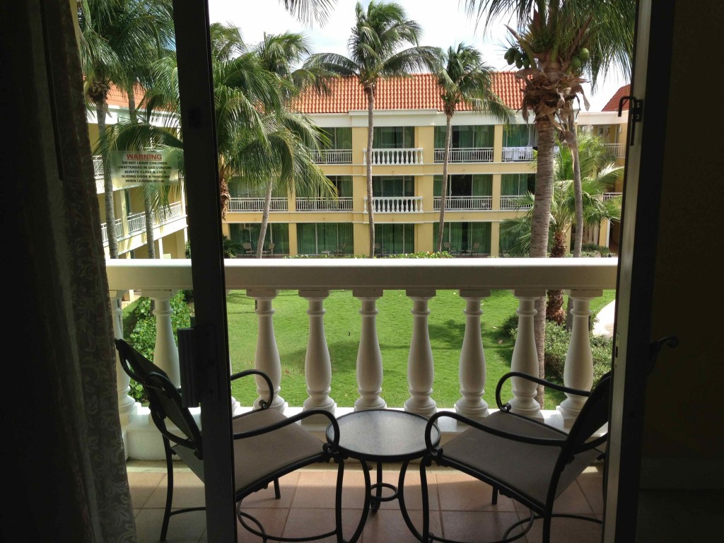 a balcony with chairs and a table and palm trees