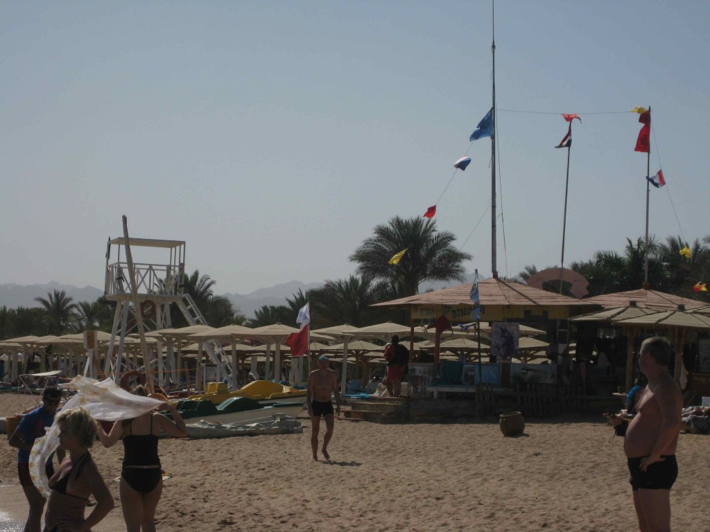 people on a beach with a lifeguard tower and a lifeguard stand