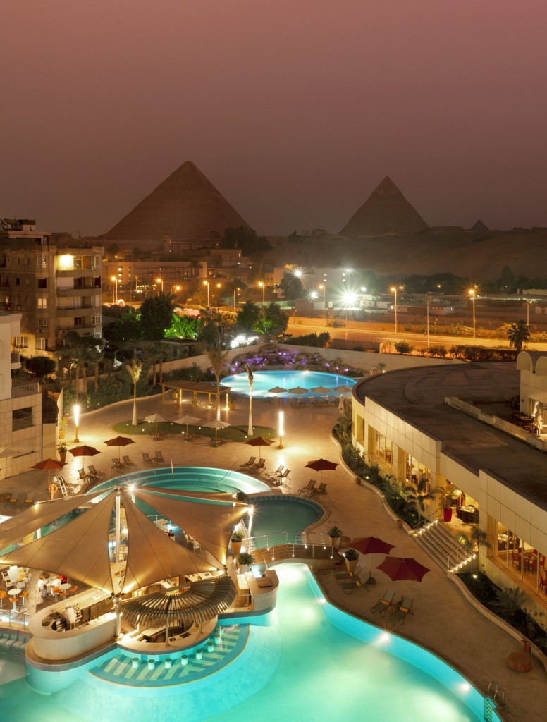 a pool and buildings with a pyramid in the background