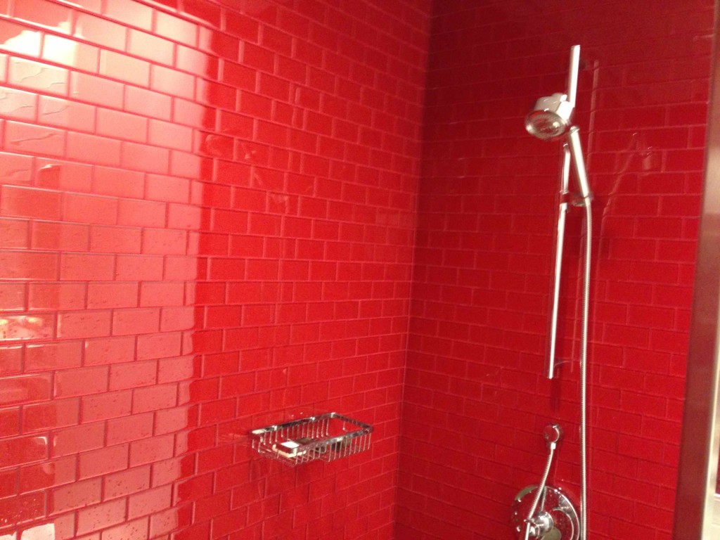 a shower with a red wall