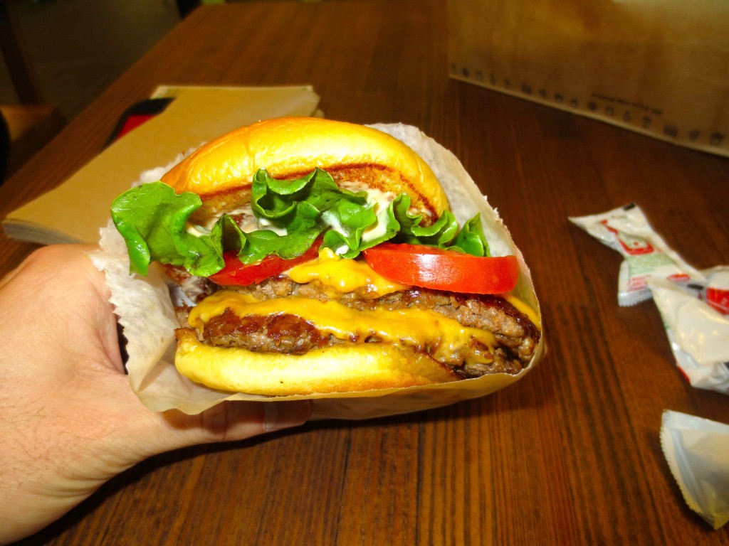 a hand holding a cheeseburger