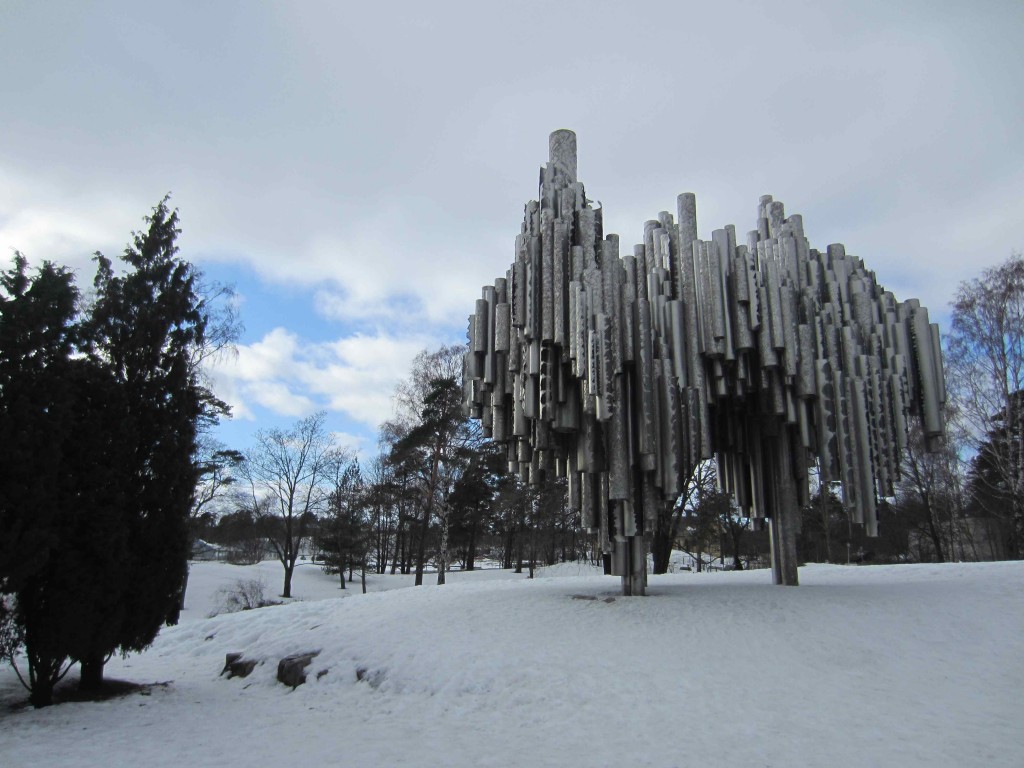 a sculpture in the snow with Sibelius Monument in the background