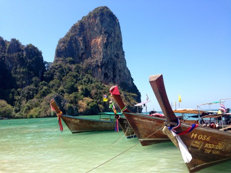 boats in the water with a large rock in the background with Railay Beach in the background
