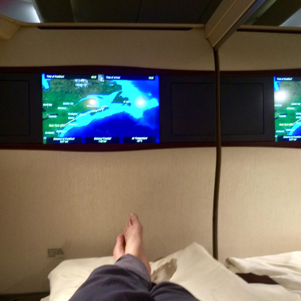 a person's feet on a bed with a screen above them