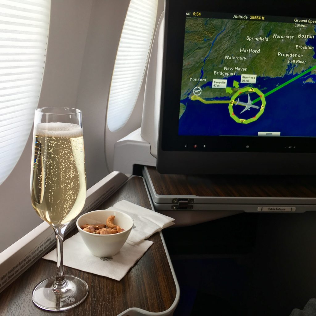 a glass of champagne and a bowl of cereal on a table in an airplane