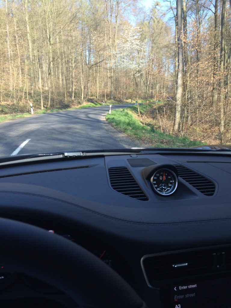 a dashboard of a car on a road with trees in the background