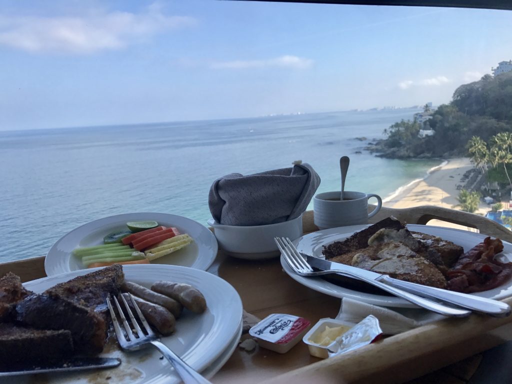 a table with plates of food and a view of the ocean