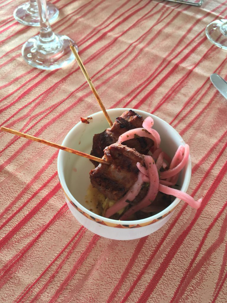 a bowl of food with two skewers