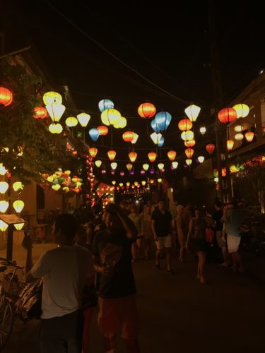 a group of people walking down a street with lanterns