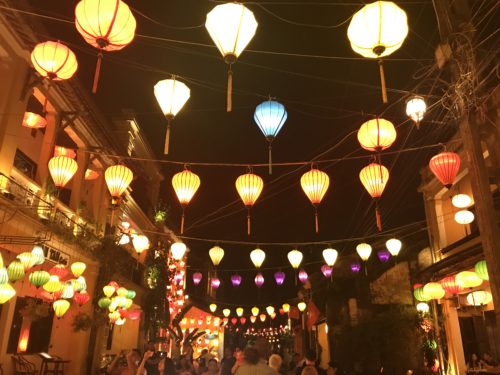 a street with lanterns and people walking around