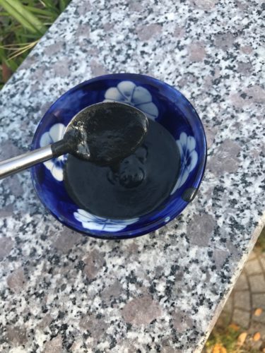 a spoon in a bowl with black liquid