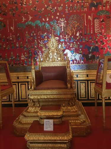 a gold throne in a room with a red wall