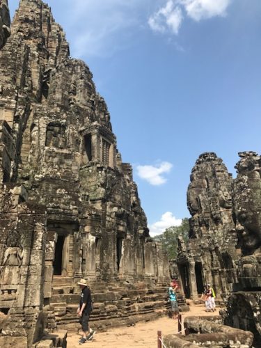 people walking in a stone building with Angkor Wat in the background