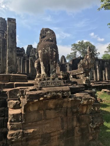 a stone statue of a lion with Angkor Wat in the background