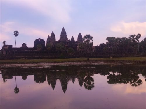 a body of water with Angkor Wat in the background