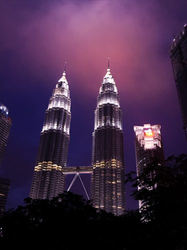 a tall buildings at night with Petronas Towers in the background