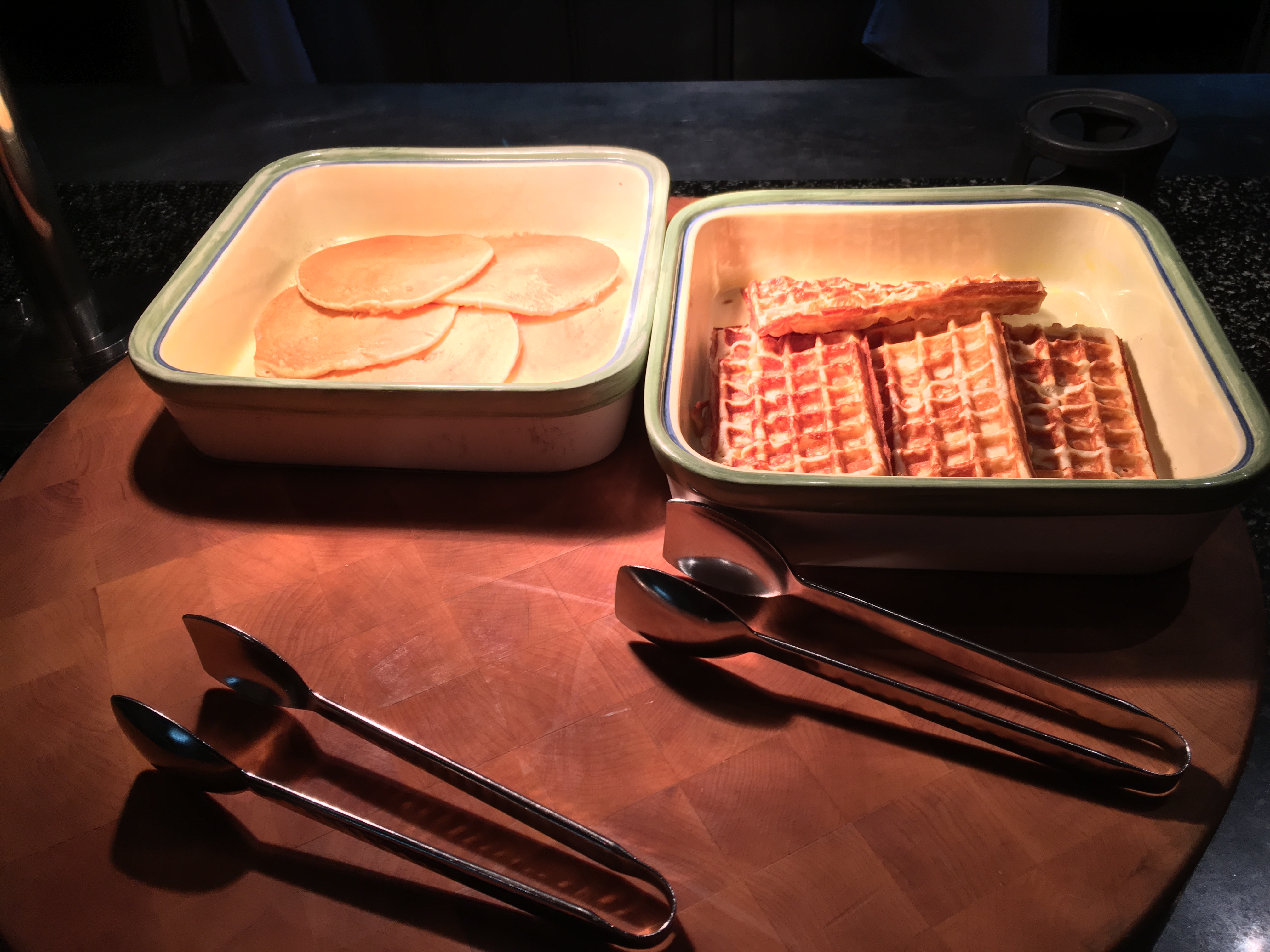 a trays of food and tongs on a table