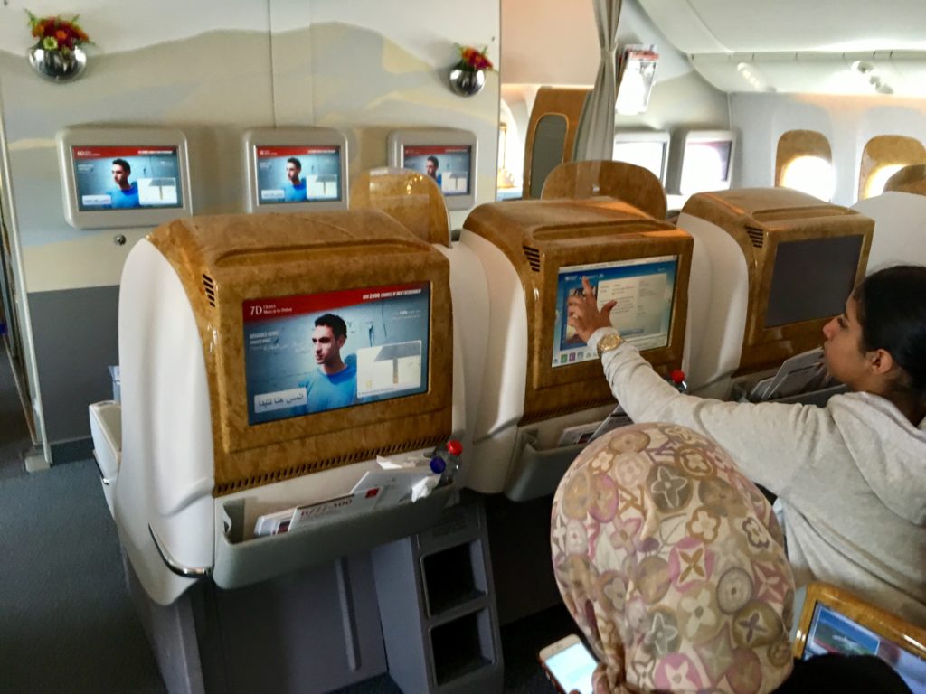 a person sitting in an airplane with a screen on the wall
