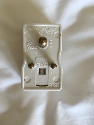 a white electrical plug with gold buttons
