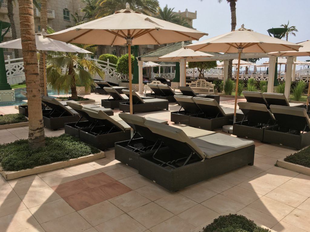 a group of lounge chairs and umbrellas on a patio