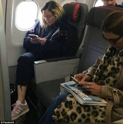 a woman sitting on an airplane looking at her phone