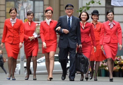 a man in a suit and a group of flight attendants walking
