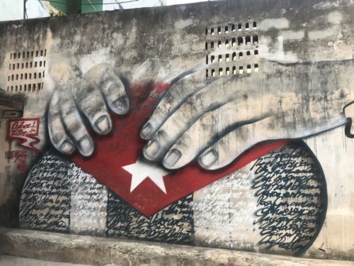a wall with a painting of hands and a flag