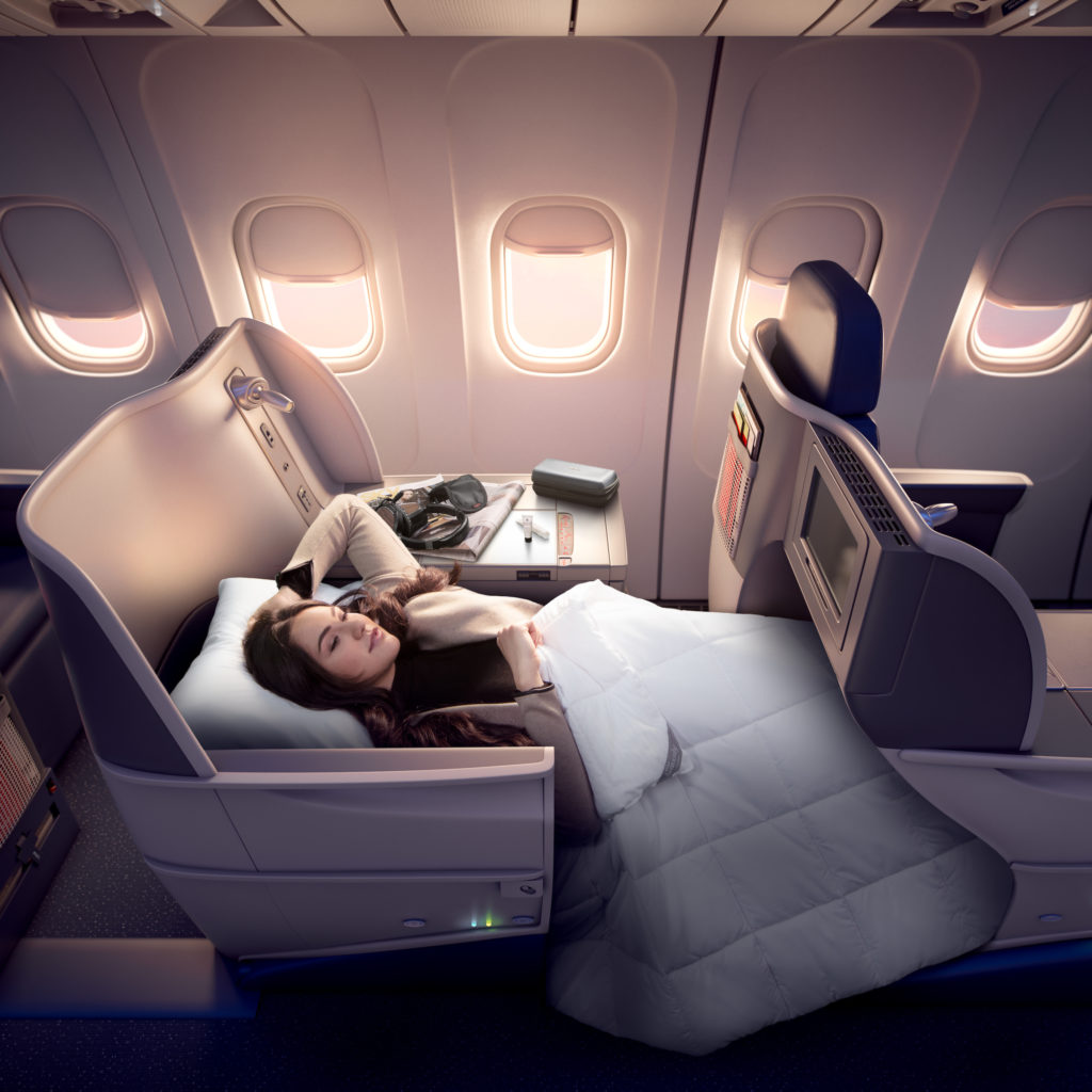 a woman lying in a bed in an airplane