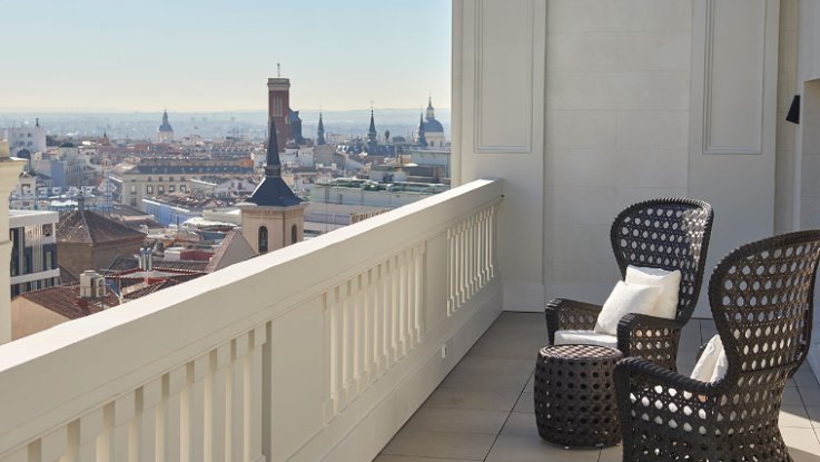 a balcony with chairs and a view of a city
