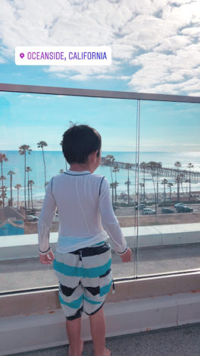 a child looking out a window at a beach