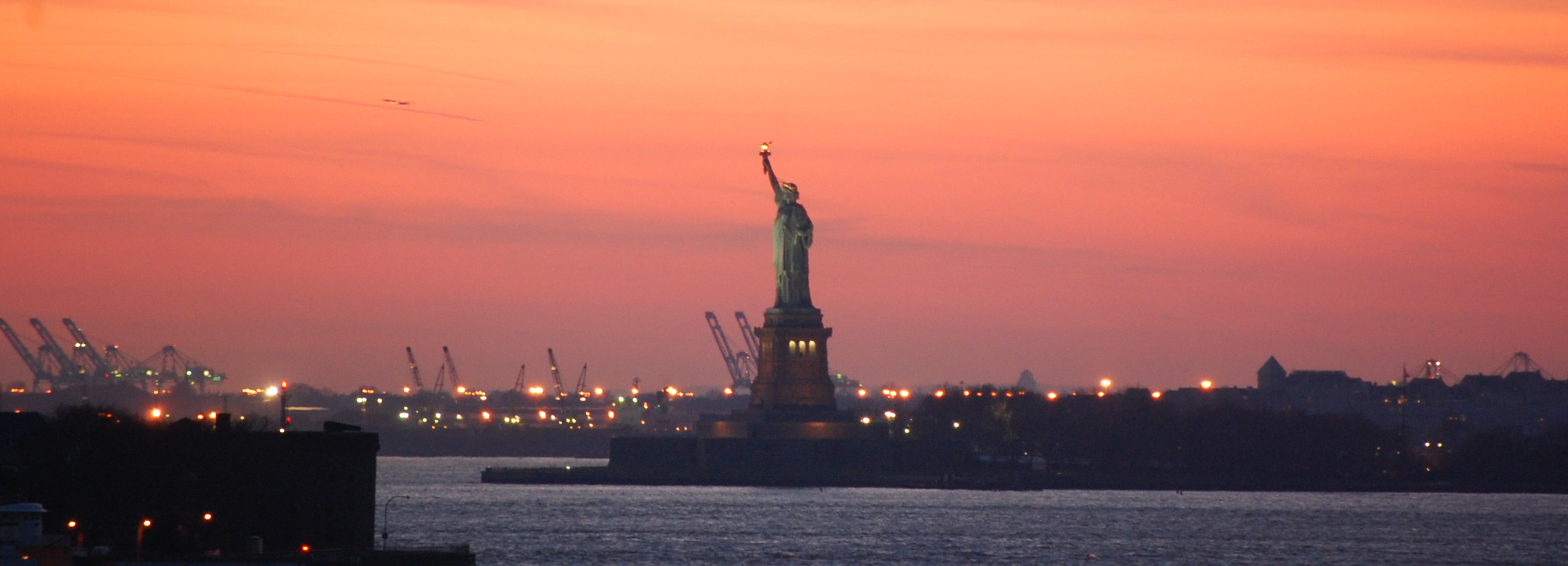 a statue of liberty with a sunset sky
